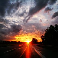 View of road against cloudy sky at sunset