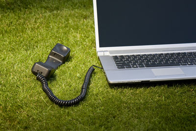 Telephone receiver connected to laptop on land