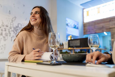 Portrait of a smiling young woman with drink on table