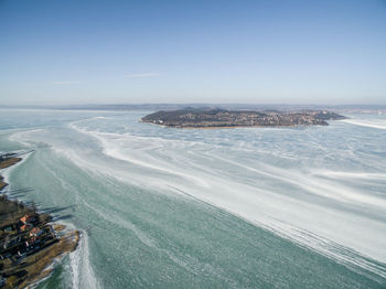 Aerial view of city by sea against sky