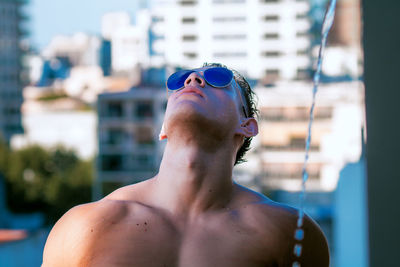 Close-up of shirtless man wearing sunglasses against sky