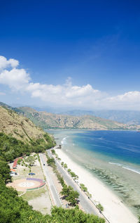 High angle view of road by sea against blue sky