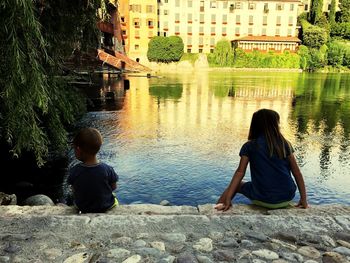 Rear view of women sitting by lake