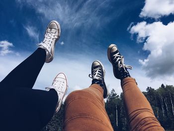 Low section of friends with feet up against blue sky