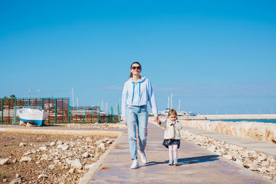 Mother and son on shore against clear sky