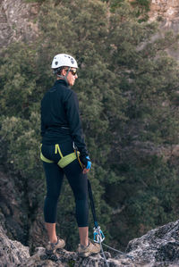 Concept: adventure. female climber with helmet and harness. thoughtful standing on a rock on top of the mountain. solar luminous flare. via ferrata in the mountains.