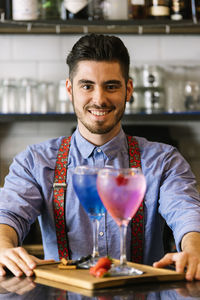 Portrait of male bartender serving drinks at bar counter