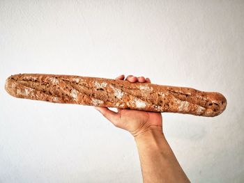 Close-up of hand holding bread against white background
