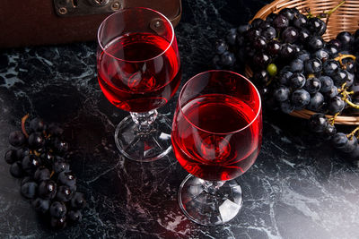 Red wine and grapes in glass on table