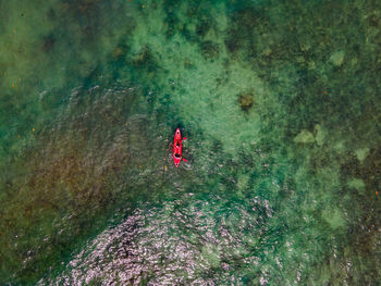 The top view of two tourist paddling their red kayak at the beautiful blue seashore in summer