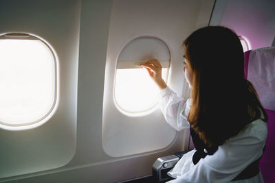 Rear view of woman looking through window