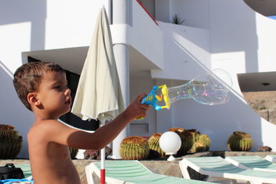 Side view of shirtless boy holding bubble wand