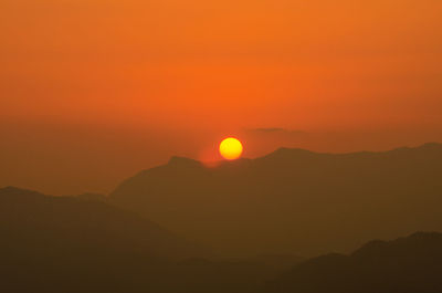 Scenic view of silhouette mountains against orange sky