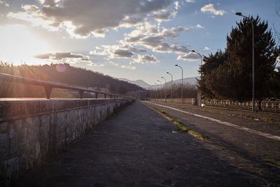 Empty road along trees and against sky