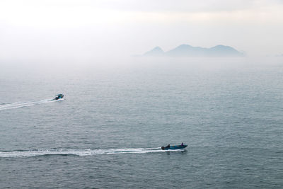 High angle view of boats on sea against sky during foggy weather