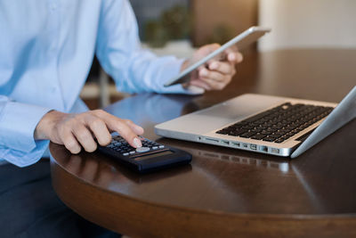 Midsection of man using mobile phone on table