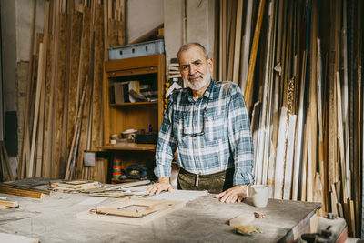 Portrait of confident male carpenter standing in repair shop