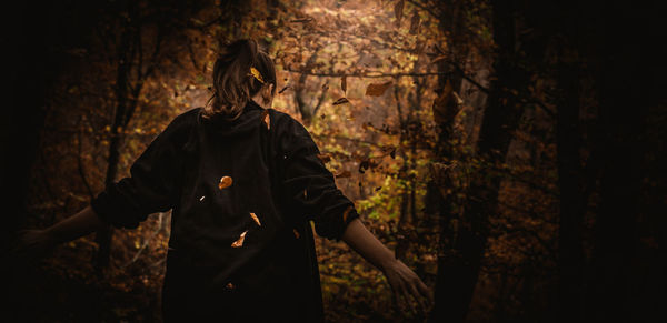 Rear view of woman standing in forest during autumn