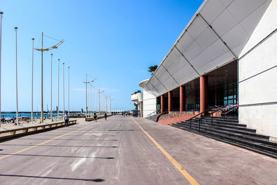 Road leading towards city against blue sky