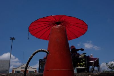 Low angle view of red umbrella against blue sky