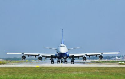 Airplane on airport runway against clear blue sky