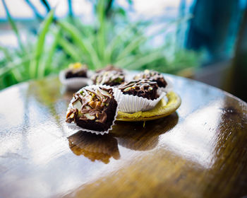 Chocolate brownie cubes with chocolate drizzle in paper cups on a wooden background.