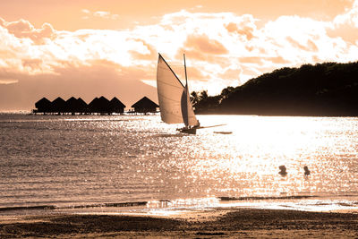 Silhouette sailboat sailing on sea against sky during sunset