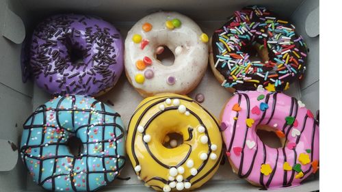 High angle view of multi colored donuts on box..