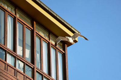 Low angle view of built structure against clear blue sky and a seagull