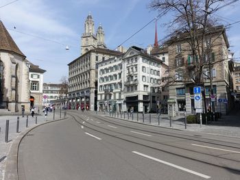 Empty road in city against cloudy sky