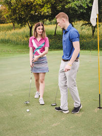 Full length of young couple playing golf