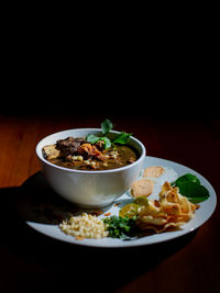 Close-up of indonesian food in plate on table against black background