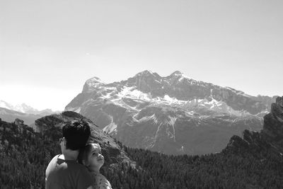 Father and daughter on mountain against clear sky