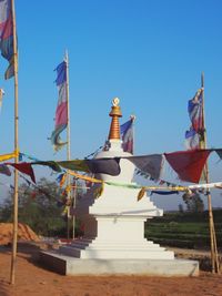 Low angle view of flags against clear blue sky