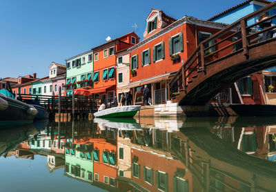 Buildings by canal against sky in city