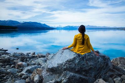 Rear view of woman looking at lake against sky