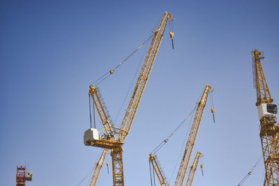 Low angle view of crane against clear blue sky