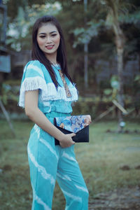 Portrait of young woman smiling while standing on field