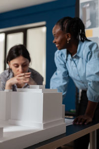 Young woman using mobile phone while sitting on table