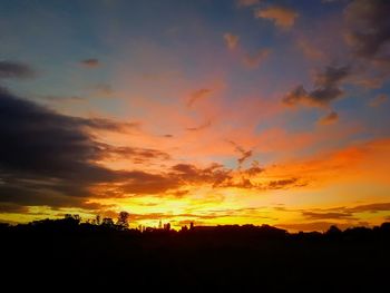 Silhouette trees against dramatic sky during sunset