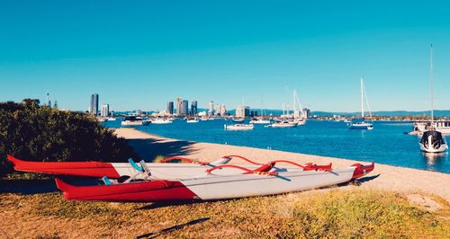 Sailboats moored in sea against clear blue sky