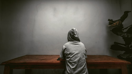 Rear view of woman standing against wall at home