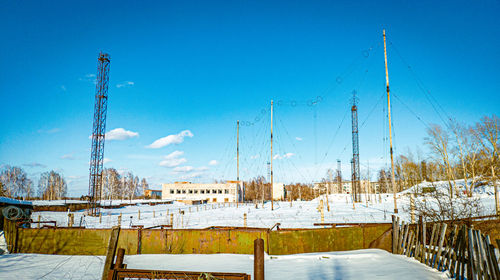 Snow covered field against blue sky communication towers in the snowdrifts behind the fences