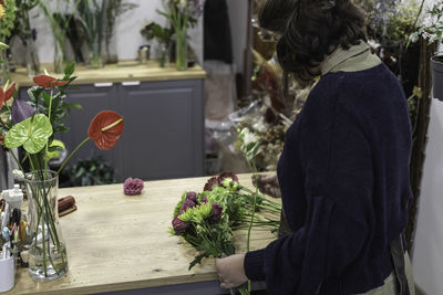 Rear view of woman standing by potted plants