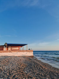 Lifeguard hut on beach against blue sky