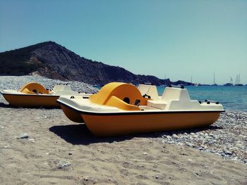 Boat moored on beach against clear sky