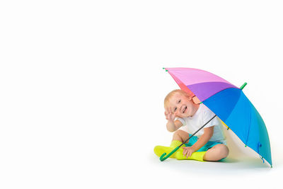 Midsection of woman holding umbrella against white background