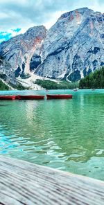 Scenic view of lake by snowcapped mountains against sky