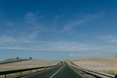 Road leading towards landscape against sky