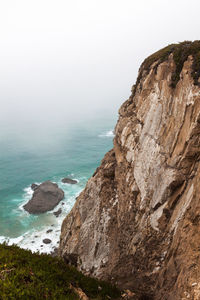 Rock formations by sea against clear sky